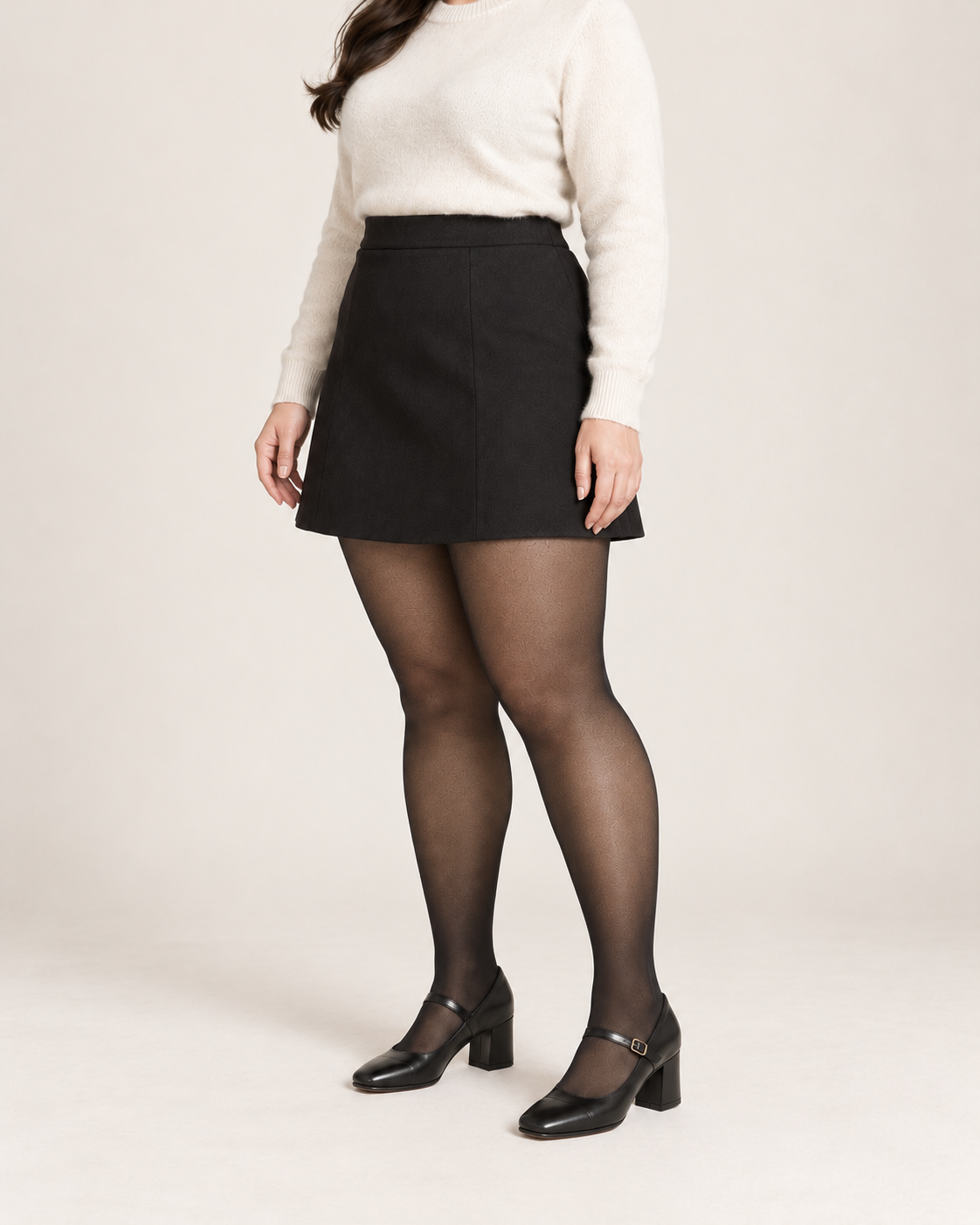 Midnight tights on a fuller-figure adult model in an ivory sweater and skirt, three-quarter studio view; Plus styling illustration
