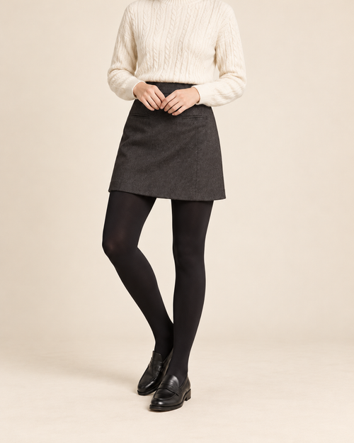 Onyx opaque black tights with a charcoal skirt, ivory sweater and black loafers; shoulders-down view